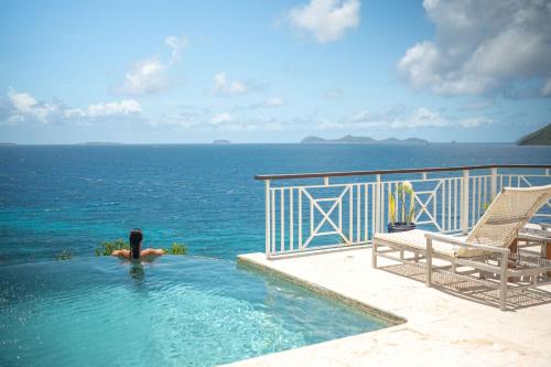 a person in a swimming pool overlooking the ocean at Scrub Island Resort, Spa & Marina in The Mill