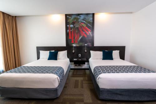 a hotel room with two beds with blue pillows at Wyndham Quito Airport in Tababela