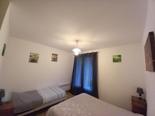 a bedroom with two beds and a blue curtain at Auberge les rastels in Savournon
