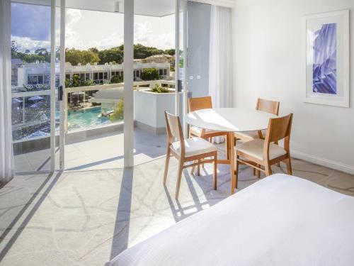 a dining room with a table and chairs and a balcony at Sofitel Noosa Pacific Resort in Noosa Heads