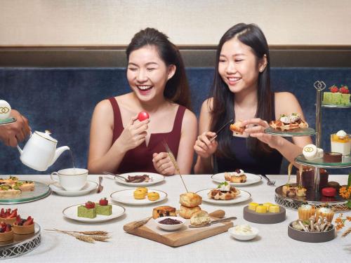 two women sitting at a table eating food at Sofitel Singapore City Centre in Singapore