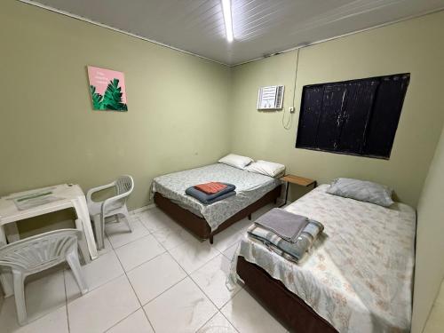 a room with two beds and a table and a desk at Hotel e Restaurante Casa Paraense Original, px ao aeroporto in Manaus
