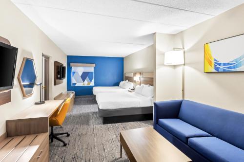 a hotel room with a blue couch and a bed at Holiday Inn Express Hotel & Suites Charleston-Southridge by IHG in Charleston