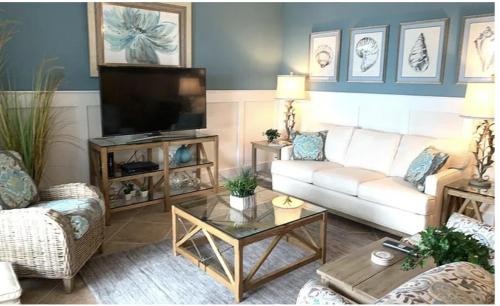a living room with a white couch and a flat screen tv at Sunny First-Floor Condo in Bonita National with Golf & Social Membership Ideal 30-Night Stay in Bonita Springs