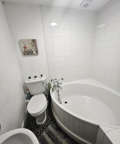 a bathroom with a white tub and a toilet and a bath tub at Sensinhome in Dover