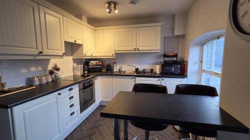 a kitchen with white cabinets and a black counter top at Sensinhome in Dover