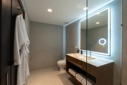 a bathroom with a toilet and a sink and a mirror at Wyndham Quito Airport in Tababela