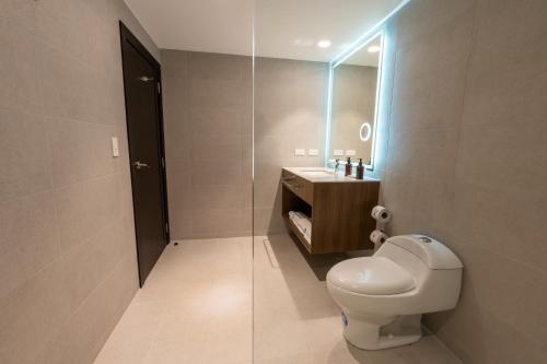a bathroom with a toilet and a sink and a mirror at Wyndham Quito Airport in Tababela