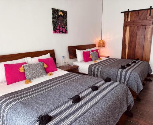two beds in a room with pink and grey at Casa Beu in Puerto Escondido