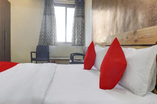 a bedroom with red pillows on a white bed at Hotel O Aarambh in Pune