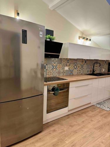 a kitchen with a stainless steel refrigerator and wooden floors at Spacieux & cozy, wifi gratuit, parking, proximité plage 15 min in Puget-sur Argens