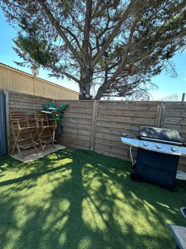 a backyard with a fence and a grill and a tree at Spacieux & cozy, wifi gratuit, parking, proximité plage 15 min in Puget-sur Argens