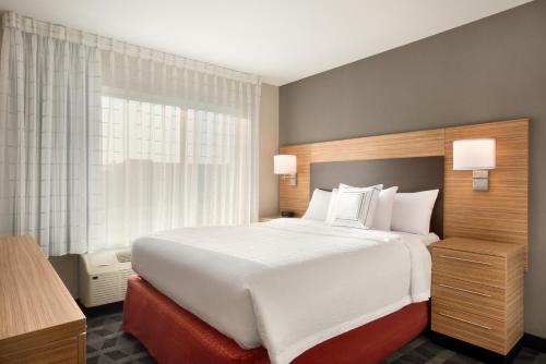 a large white bed in a room with a window at TownePlace Suites by Marriott Milwaukee Grafton in Grafton