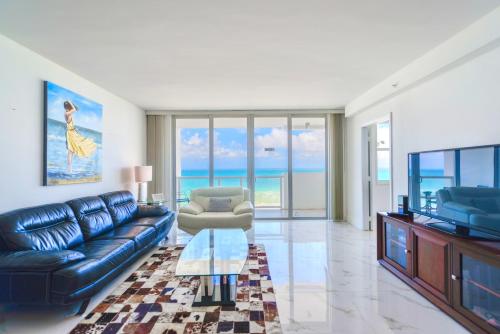a living room with a blue leather couch and a television at Ocean Breeze Retreat in Miami Beach in Miami Beach