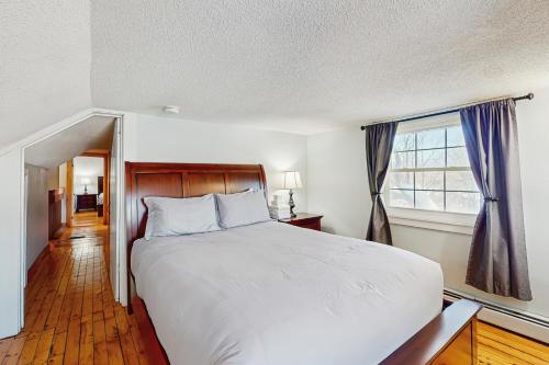 Un dormitorio con una gran cama blanca y una ventana. en Harvest Farmhouse, en Stowe