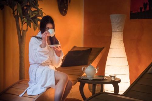 a woman sitting in a room drinking a cup of coffee at Hotel Relais Valle Orientina in Pitigliano