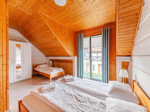 a bedroom with a large bed and a window at Comfortable holiday homes close to the beach in Grzybowo