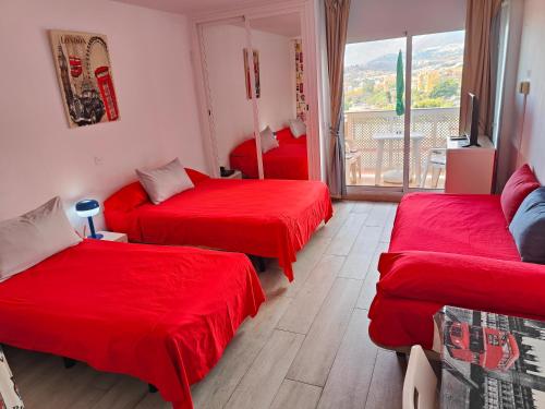 a room with three beds with red sheets at Jupiter Apartments Sea View in Benalmádena