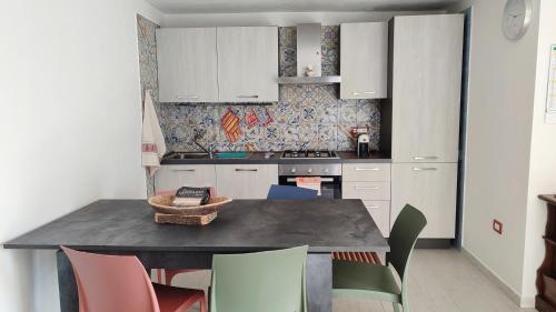 a kitchen with white cabinets and a table with chairs at Da Tziu Efisiu Mare e Relax nel Sinis in Baratili San Pietro