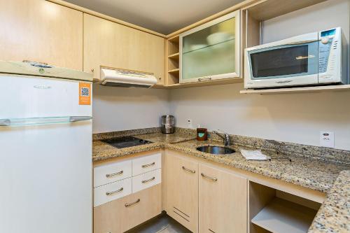 a small kitchen with a sink and a microwave at Studios modernos à beira-mar - Jurerê Beach Village JBVTOP in Florianópolis