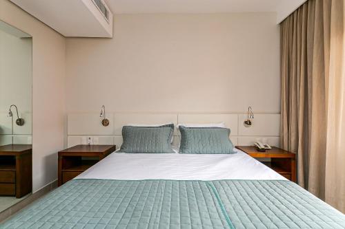 a bedroom with a large bed with blue pillows at Studios modernos à beira-mar - Jurerê Beach Village JBVTOP in Florianópolis