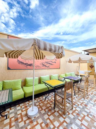 a patio with a couch and tables and umbrellas at Sun Hostel in Marrakech