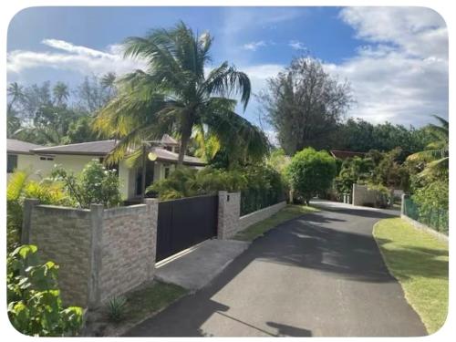 a house with a fence and a palm tree at FARE TITAINA in Hauru