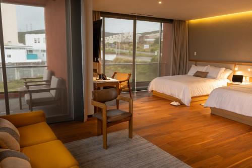 a hotel room with two beds and a desk and a window at S22 Hotel & Suites in San Luis Potosí