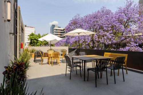 a patio with tables and chairs and purple trees at Lamartine 205 by Wynwood House in Mexico City