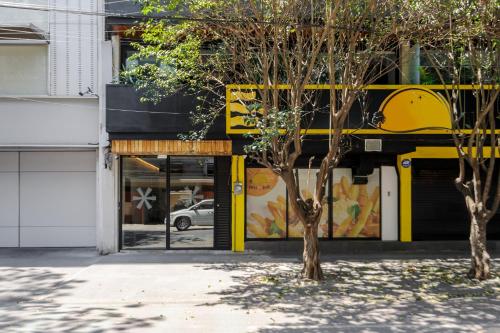 a building with yellow doors and a tree at Lamartine 205 by Wynwood House in Mexico City