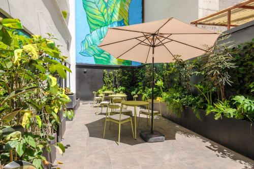 a patio with tables and chairs with an umbrella at Colima 340 by Wynwood House in Mexico City