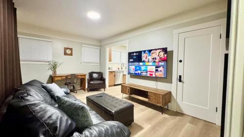 a living room with a leather couch and a flat screen tv at Downtown Historic Spanish Bungalow, with Parking in San Jose