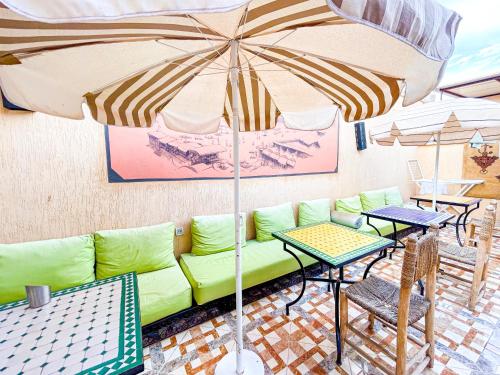 a patio with a couch and tables and an umbrella at Sun Hostel in Marrakech