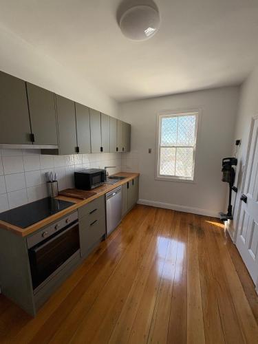 an empty kitchen with wooden floors and a large window at The Hidden Nook in Armidale