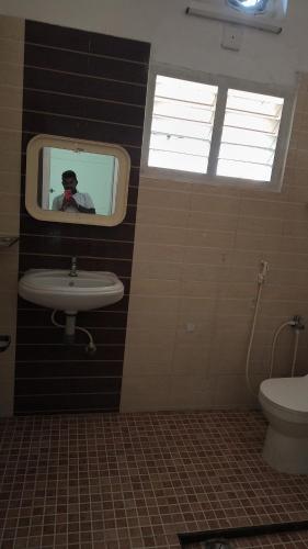 a man taking a picture of a bathroom with a sink at Pks Grand Park in Coimbatore