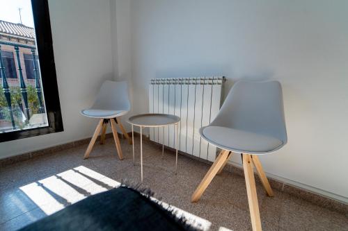two chairs and a table in a room with a window at Olmedo Hostal Plaza in Olmedo