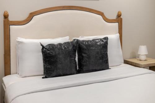 a bed with four black pillows on it at Olympia Hotel by Lodgo in Montréal