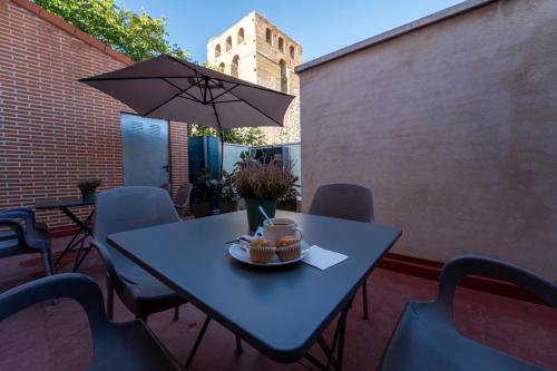 a blue table with a bowl of fruit and an umbrella at Olmedo Hostal Plaza in Olmedo