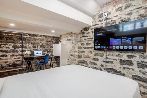 a bedroom with a large tv on a stone wall at Olympia Hotel by Lodgo in Montréal