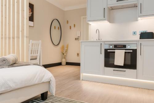 a white kitchen with a stove top oven next to a bed at Royal Oakwood Studio 1 Bed Brighton Sleeps 2 in Brighton & Hove