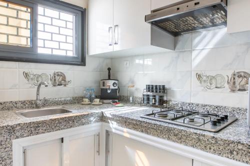 a white kitchen with a sink and a stove at Cosy Apartment - Calm & Central, Parking, Garden in Agadir