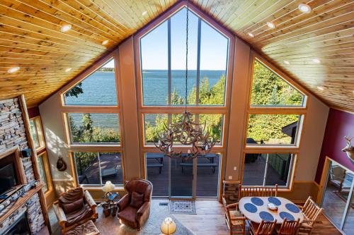 a large room with large windows and a table and chairs at Spacious Leech Lake Home on 2 Private Acres, 200' of lake shore 15 Minutes to Walker with boat lift, dock, swimming, fire pit in Walker