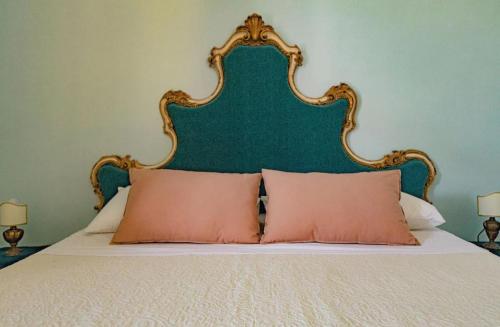 a bed with a green headboard and two pink pillows at Luxury Suite Vitruvio 55 in Formia
