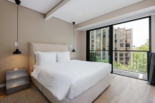a bedroom with a white bed and a large window at Nuevo Leon 155 by Wynwood House in Mexico City