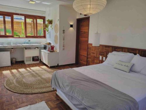 a bedroom with a large bed and a sink at Chalé Koa Flora - PRAIA DE MOITAS in Amontada