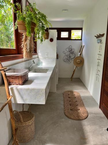 a white kitchen with a sink and a rug at Chalé Koa Flora - PRAIA DE MOITAS in Praia de Moitas
