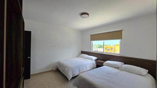una camera da letto con due letti e una finestra di Paraíso Liverte 203 a Cancún