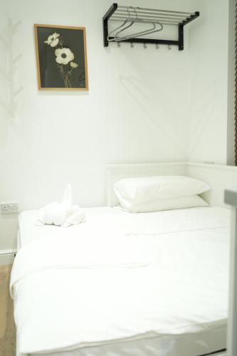 a bed with white sheets and a picture on the wall at Concept Rooms in Enfield