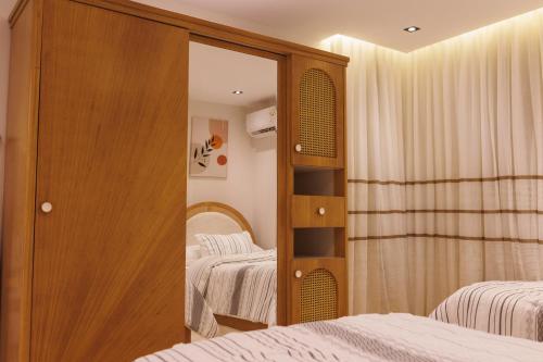 ein Schlafzimmer mit zwei Betten und einem Spiegel in der Unterkunft شقة فندقية فاخرة شارع جيهان الرئيسي بجوار النيل و جامعه المنصوره in Mansoura