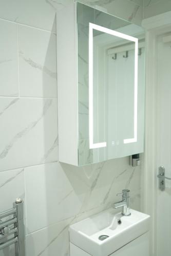 a white bathroom with a sink and a mirror at Concept Rooms in Enfield
